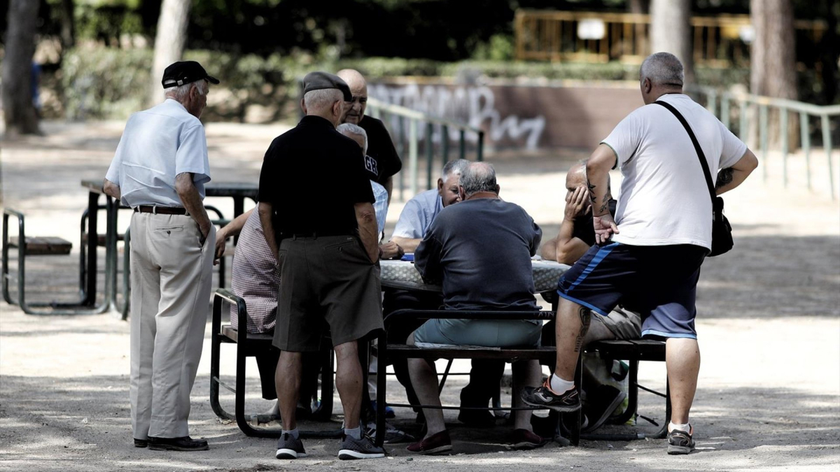 Grupo de personas mayores reunidas alrededor de una mesa en un parque